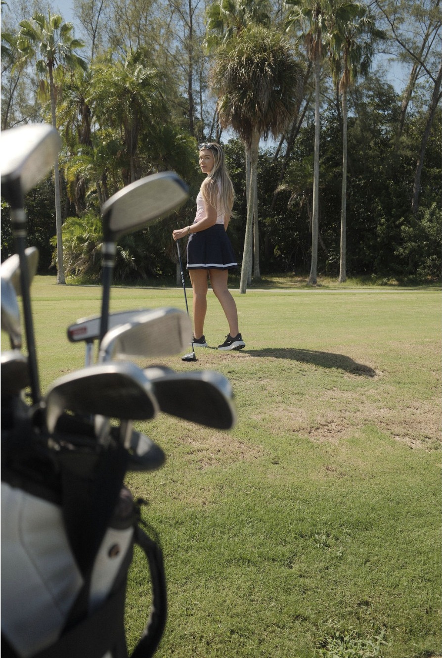 Kendall mid-swing on a palm-lined fairway